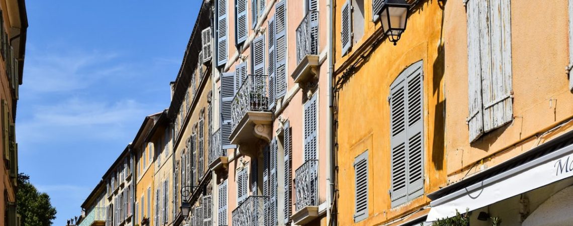 Colorful historic buildings on a sunny street in Aix-en-Provence, showcasing French architecture.