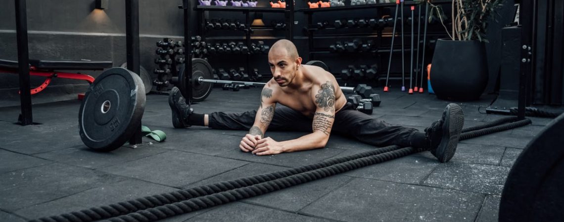 A shirtless man stretches in a modern indoor gym in Mexico City, showcasing fitness and determination.
